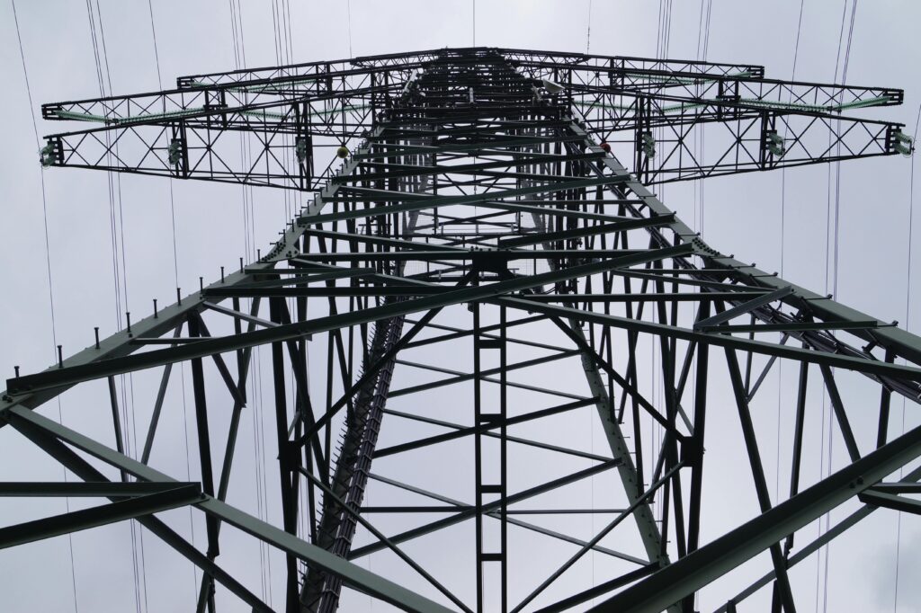 Close-up low angle view of a metal electricity pylon against a cloudy sky.